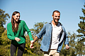 Smiling young couple walking in public park