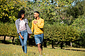 Smiling young couple walking together in public park