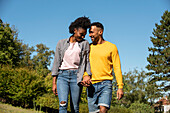 Smiling young couple with holding hands walking in public park