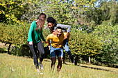 Lächelnde junge Freunde haben Spaß beim Spazierengehen in einem öffentlichen Park
