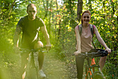 Lächelndes junges Paar beim Radfahren im Wald