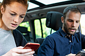 Anxious young couple using smart phones