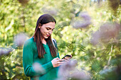 Smiling young woman text messaging on smartphone