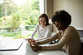 Smiling young women using digital tablet at home