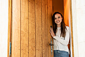 Portrait of smiling young woman standing near door