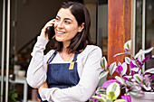 Female entrepreneur talking on smart phone while standing in garden center