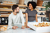 Bakery coworkers smiling at each other while standing behind counter