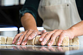Niedriger Blickwinkel auf die Hände einer Bäckerin beim Kneten von Gebäck