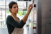 Mid-shot of female Latin-American bakery owner setting oven's timer for pastry