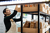 Mittelaufnahme einer lateinamerikanischen Bäckereibesitzerin, die ihre Waren kontrolliert