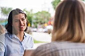 Mittelaufnahme einer lateinamerikanischen Angestellten, die mit ihrem Kollegen in einem Büro im Freien über berufliche Angelegenheiten spricht