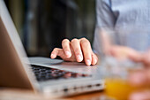 Close-up shot of woman's hand typing on laptop computer at outdoors office