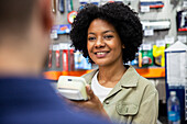 African American female hardware shop worker attending customer at store
