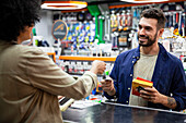 Male customer paying with credit card to African American hardware shop worker