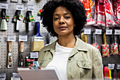 African American female hardware shop owner looking at the camera while taking inventory