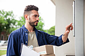 Delivery man standing in front of doorway while ringing doorbell