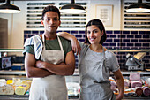 Confident grocery store owners looking at the camera while standing indoors