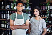 Latin American liquor store owner standing next to partner while looking at the camera