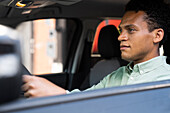 Seitenaufnahme eines gut aussehenden afroamerikanischen Mannes in seinem Auto auf dem Weg zur Arbeit