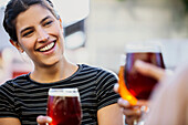Smiling young adult woman toasting beer cups with friends
