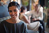 Portrait of attractive Latin-American woman looking at camera with her female friends in the background