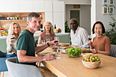 Gruppe verschiedener älterer Freunde, die sich zum Mittagessen in der Küche treffen