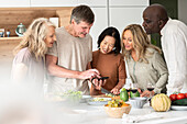 Diverse group of middle-aged friends checking a recipe while cooking