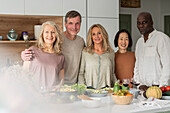 Group portrait of diverse senior friends standing at kitchen island after cooking