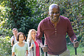 Älterer afroamerikanischer Mann mit Wanderstöcken, der mit einer Gruppe verschiedener älterer Freunde eine Wanderung unternimmt