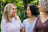 Drei Frauen mittleren Alters unterhalten sich freundlich in ihrem Hinterhof