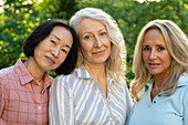 Gruppe von drei Frauen mittleren Alters, die für ein Foto im Garten posieren