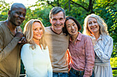 Group of diverse happy senior friends posing for photo outdoors at sunset