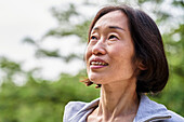 Ältere asiatische Frau schaut im Freien stehend nach oben