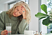 Ältere Frau mit Kopfschmerzen im Esszimmer sitzend