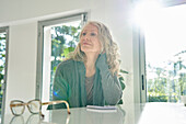 Thoughtful senior woman sitting at counter during daytime