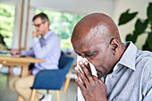 Close-up shot of senior African-American man with a cold blowing his nose