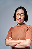 Reife asiatische Frau, die mit verschränkten Armen in die Kamera schaut
