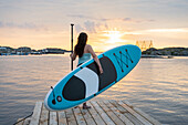 Woman carry paddleboard on jetty