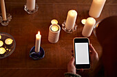 Woman using phone next to lit candles