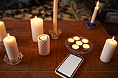 Smart phone and lit candles on table
