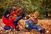 Friends playing with autumn leaves in park