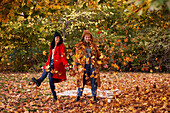 Friends playing with autumn leaves in park