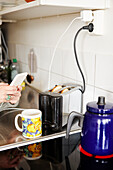 Hands holding cell phone over kitchen worktop