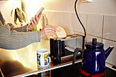 Woman putting bread slices in toaster