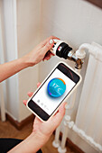 Woman using thermostat and app on phone