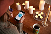 Woman lighting candles and using temperature app