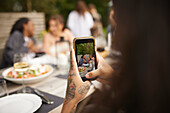 Person photographing friends at table