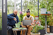 Men using laptop in greenhouse