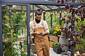 Man using cell phone in front of greenhouse