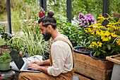 Mann mit Laptop im Gewächshaus